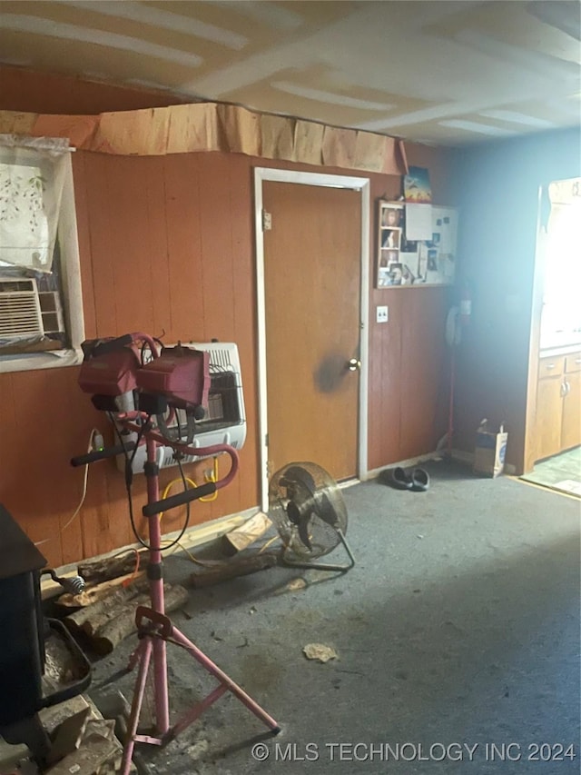 misc room featuring cooling unit, a wood stove, and wood walls