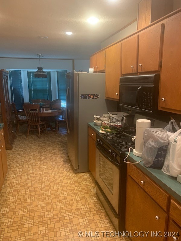 kitchen with light tile patterned flooring, stove, and stainless steel refrigerator