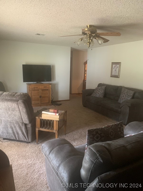 carpeted living room with ceiling fan and a textured ceiling