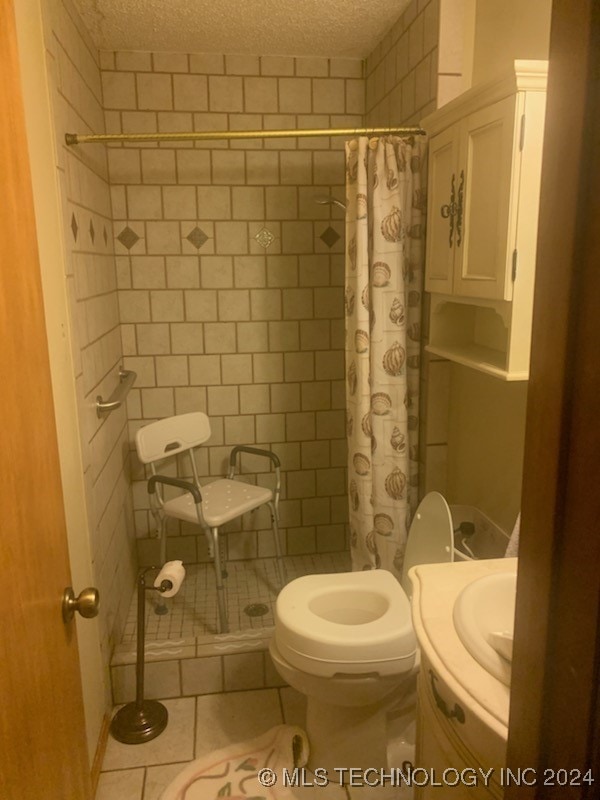 bathroom with tile patterned floors, curtained shower, a textured ceiling, and toilet