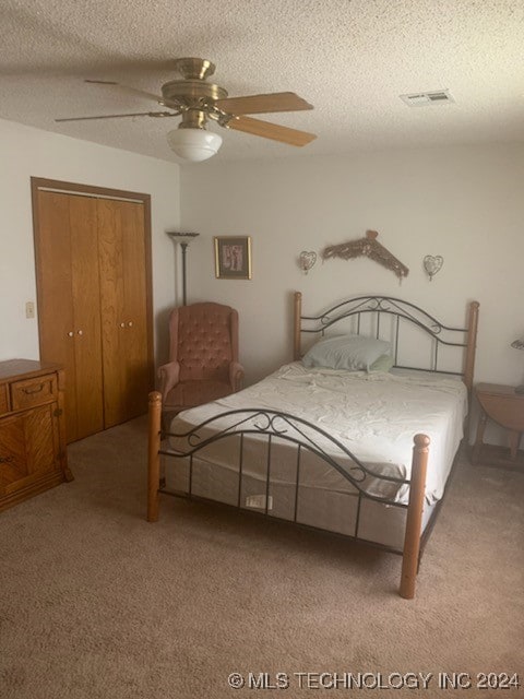 carpeted bedroom with ceiling fan, a closet, and a textured ceiling