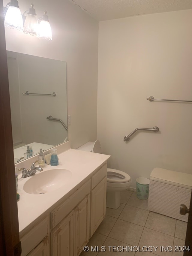 bathroom with tile patterned flooring, a textured ceiling, vanity, and toilet