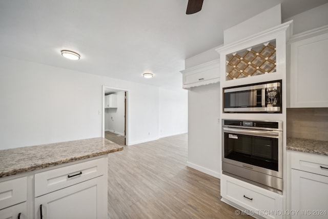 kitchen with white cabinets, appliances with stainless steel finishes, light stone counters, light hardwood / wood-style floors, and ceiling fan