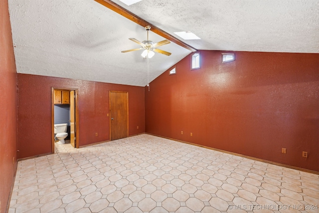 unfurnished room with a textured ceiling, ceiling fan, light tile patterned flooring, and lofted ceiling with skylight