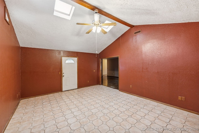 unfurnished room featuring ceiling fan, vaulted ceiling with skylight, and light tile patterned floors