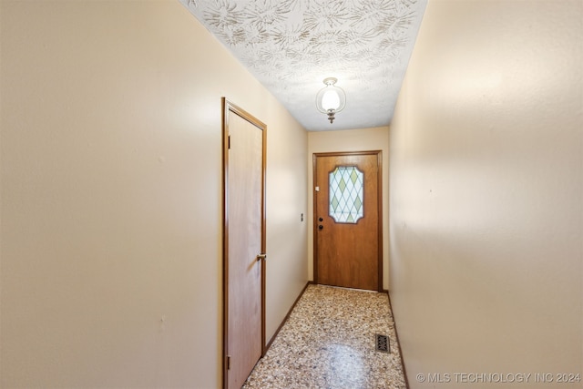 doorway to outside with tile patterned flooring and a textured ceiling