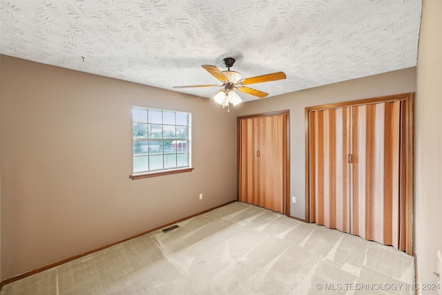 carpeted empty room with ceiling fan and a textured ceiling