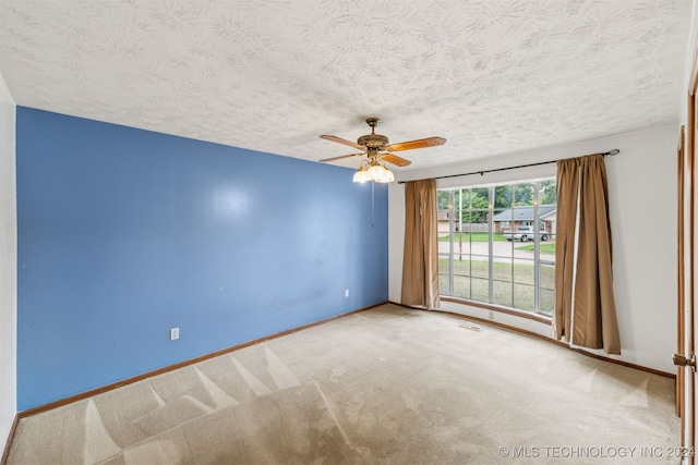 unfurnished room featuring ceiling fan, light carpet, and a textured ceiling