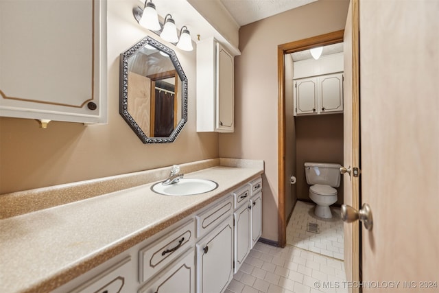 bathroom with a textured ceiling, toilet, vanity, and tile patterned floors