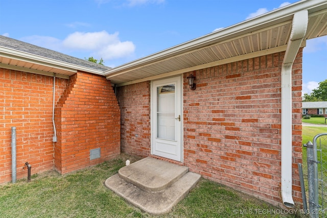 view of exterior entry featuring a lawn