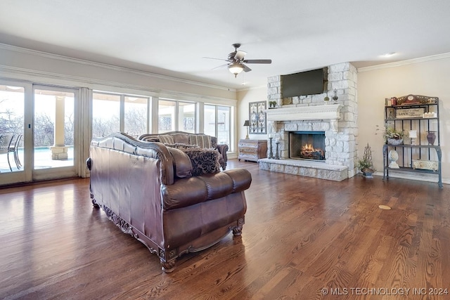 living room with crown molding, a stone fireplace, and wood-type flooring