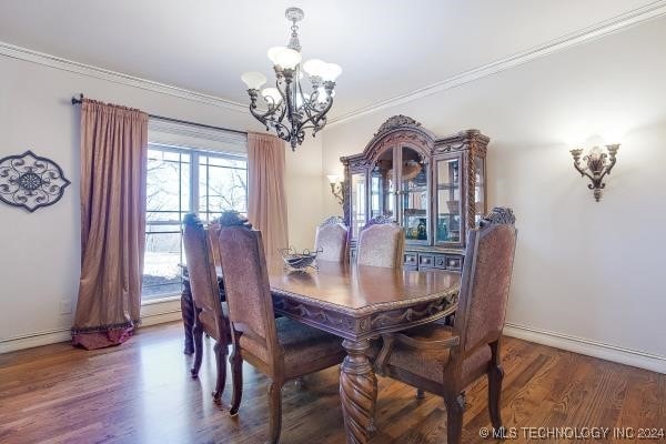 dining area with wood-type flooring, ornamental molding, and an inviting chandelier