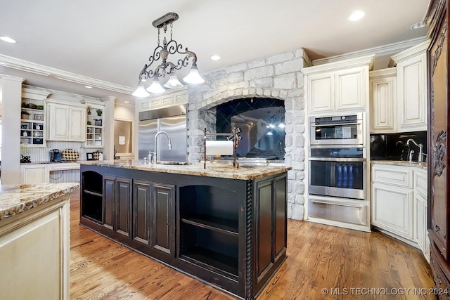 kitchen with a center island with sink, appliances with stainless steel finishes, light hardwood / wood-style floors, and crown molding