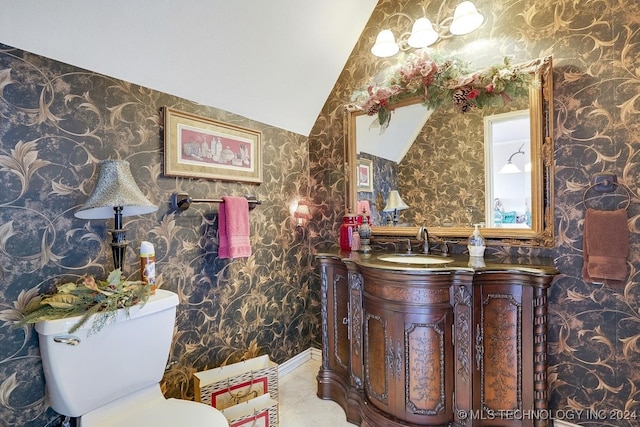 bathroom featuring tile patterned flooring, toilet, vaulted ceiling, and vanity