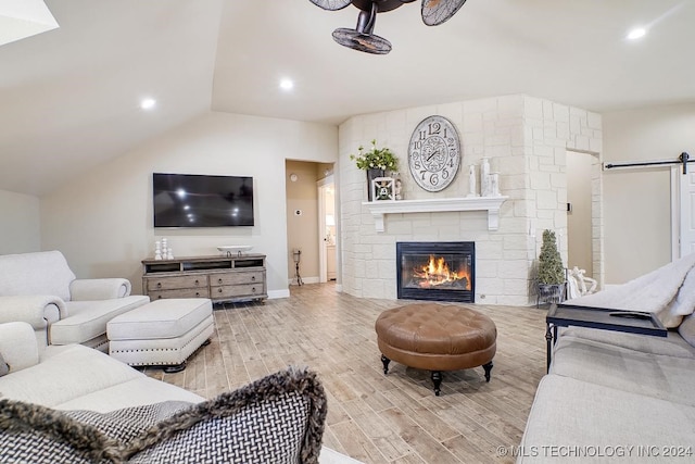 living room with a barn door, light hardwood / wood-style flooring, and a fireplace