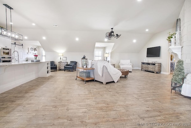 living room with plenty of natural light, vaulted ceiling, and light wood-type flooring