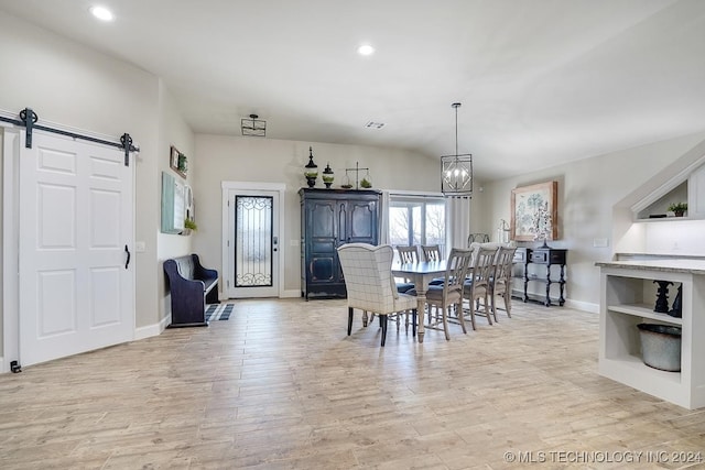 dining area with an inviting chandelier, light hardwood / wood-style floors, and a barn door