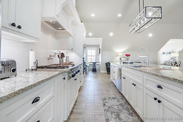 kitchen featuring decorative backsplash, light stone countertops, stainless steel dishwasher, pendant lighting, and white cabinets