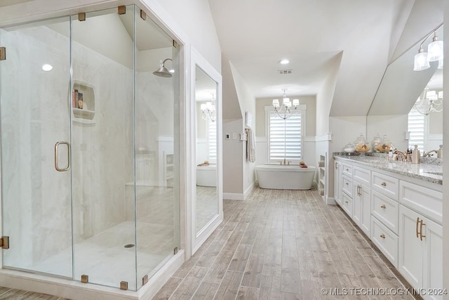 bathroom featuring plus walk in shower, vaulted ceiling, an inviting chandelier, and vanity