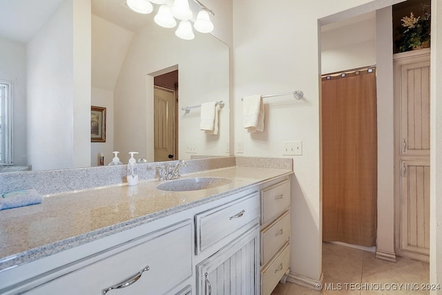 bathroom with vaulted ceiling, tile patterned flooring, and vanity