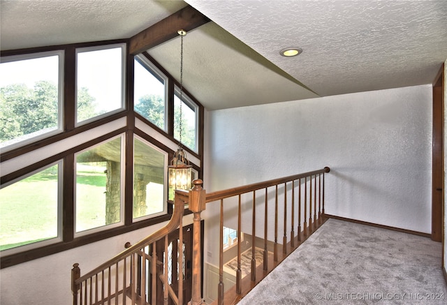 corridor featuring carpet flooring, lofted ceiling with beams, and a textured ceiling