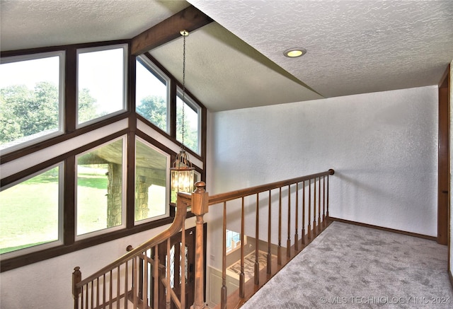 corridor with a textured ceiling, a textured wall, carpet flooring, and baseboards