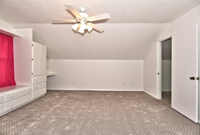 additional living space with baseboards, a ceiling fan, lofted ceiling, a textured ceiling, and carpet flooring