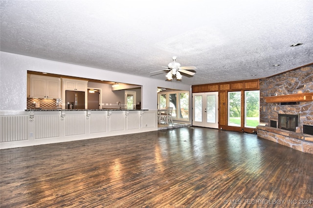 unfurnished living room featuring a textured ceiling, a fireplace, dark hardwood / wood-style floors, and ceiling fan