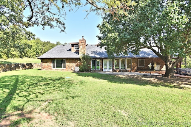 back of house featuring french doors, a lawn, and a chimney