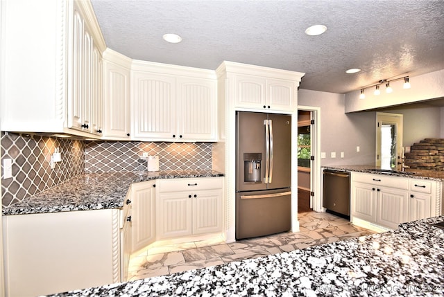 kitchen featuring stainless steel appliances, a sink, marble finish floor, backsplash, and dark stone counters