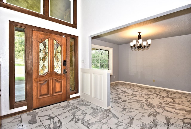 entryway with baseboards, marble finish floor, and a notable chandelier