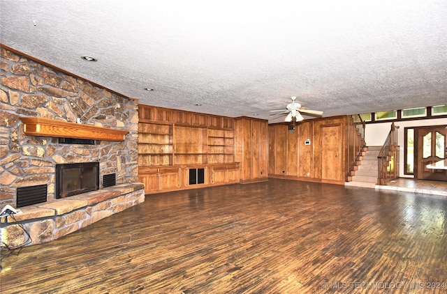 unfurnished living room with a fireplace, stairway, ceiling fan, a textured ceiling, and wood finished floors