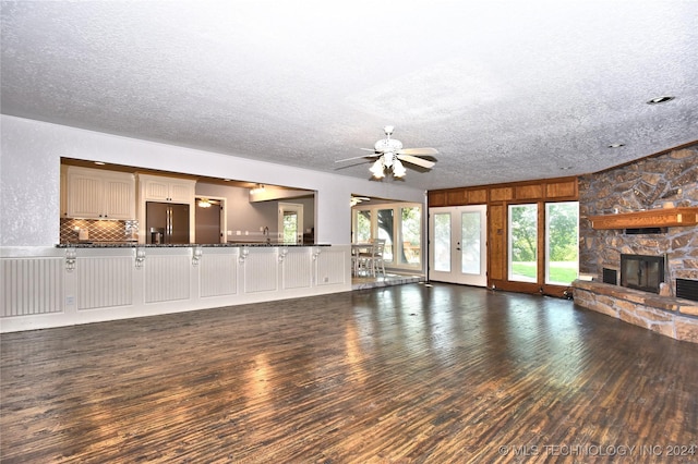 unfurnished living room featuring a textured ceiling, a fireplace, a sink, wood finished floors, and a ceiling fan