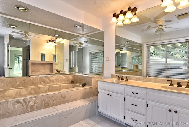 bathroom featuring a wealth of natural light, vanity, a textured ceiling, and tiled tub