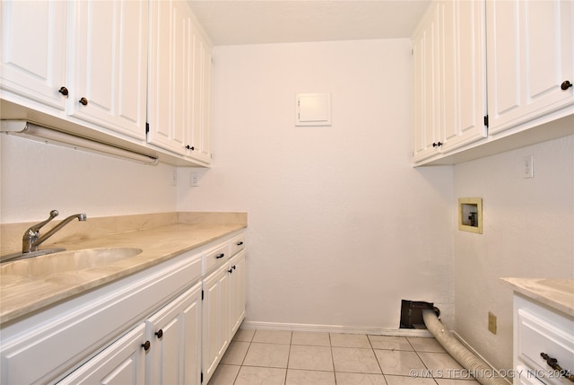 washroom with cabinets, light tile patterned flooring, hookup for a washing machine, and sink