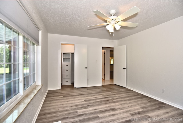 unfurnished bedroom with dark wood-type flooring, ceiling fan, and a textured ceiling