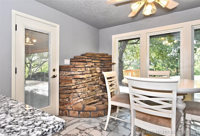 dining room with a textured wall, marble finish floor, ceiling fan, and a textured ceiling