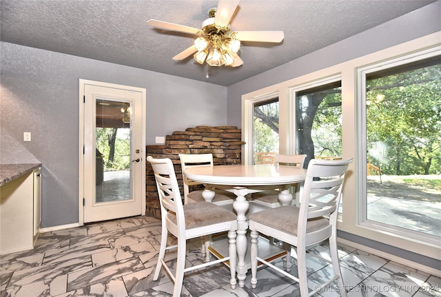 dining space featuring marble finish floor, plenty of natural light, and a textured ceiling