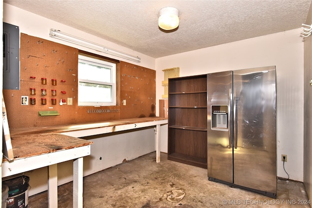 kitchen with stainless steel refrigerator with ice dispenser, electric panel, and a textured ceiling