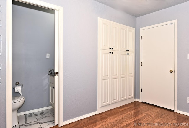 unfurnished bedroom featuring baseboards, a closet, and wood finished floors