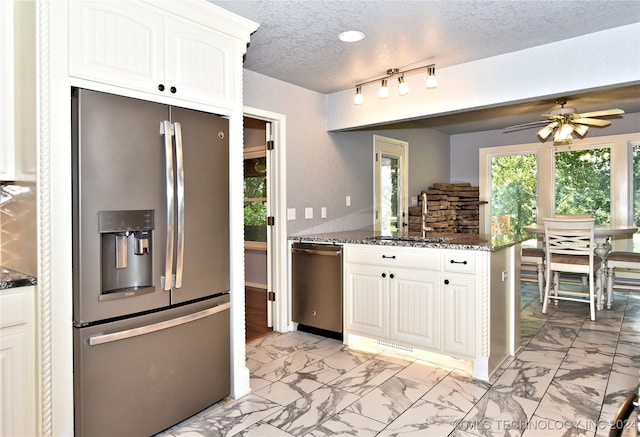 kitchen with white cabinetry, appliances with stainless steel finishes, ceiling fan, dark stone countertops, and a textured ceiling