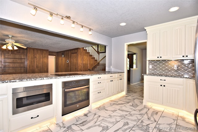 kitchen featuring decorative backsplash, a textured ceiling, ceiling fan, appliances with stainless steel finishes, and dark stone countertops