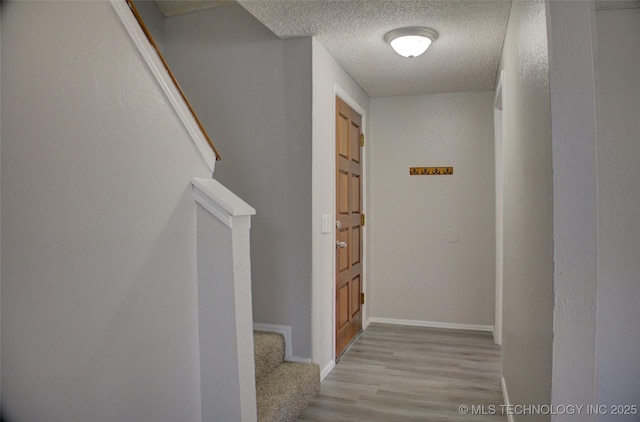 corridor featuring a textured ceiling and light wood-type flooring