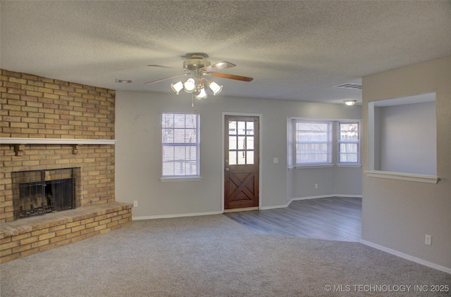 unfurnished living room featuring a brick fireplace, carpet floors, a textured ceiling, and ceiling fan