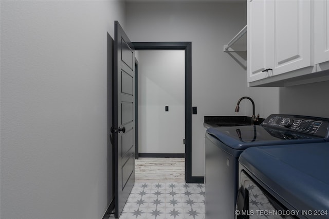 laundry room featuring cabinet space, baseboards, light floors, separate washer and dryer, and a sink