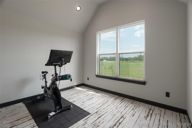 exercise area with vaulted ceiling, light wood-style flooring, and baseboards