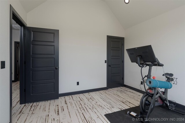 workout area with light wood-type flooring and vaulted ceiling