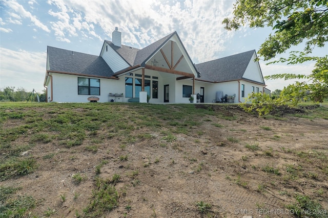 back of property with roof with shingles, a chimney, and a patio area