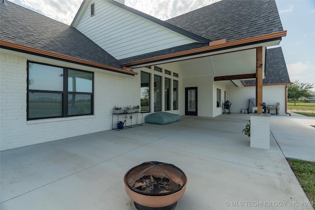 back of property with an outdoor fire pit, a patio area, brick siding, and a shingled roof