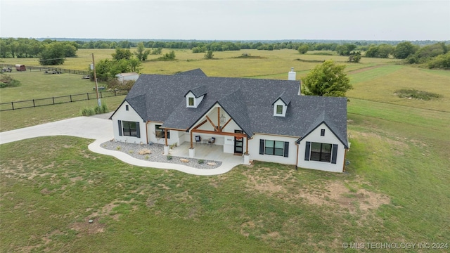 view of front facade with roof with shingles, a front yard, fence, and a rural view